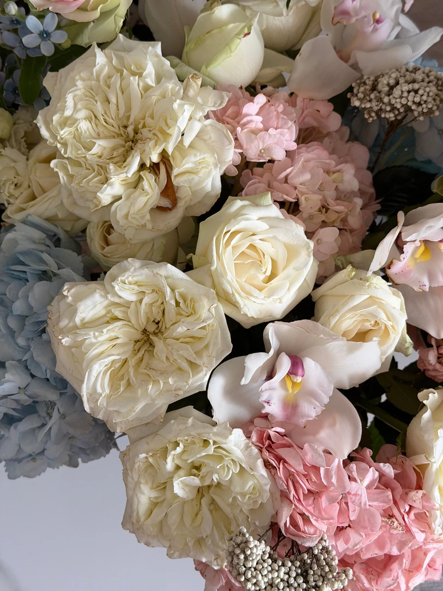 Ivory roses, pastel hydrangeas and pink orchids in a floral arrangement