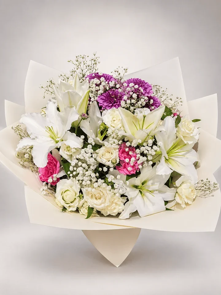 Grace: White lilies and roses with pink and purple accents in understated ivory wrapping.